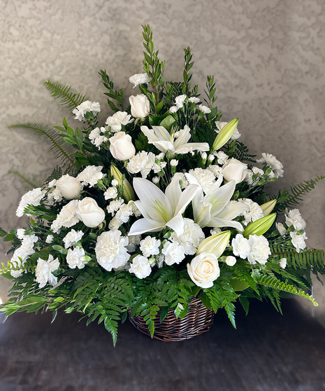 White lilies and other white flowers in a funeral/sympathy basket.