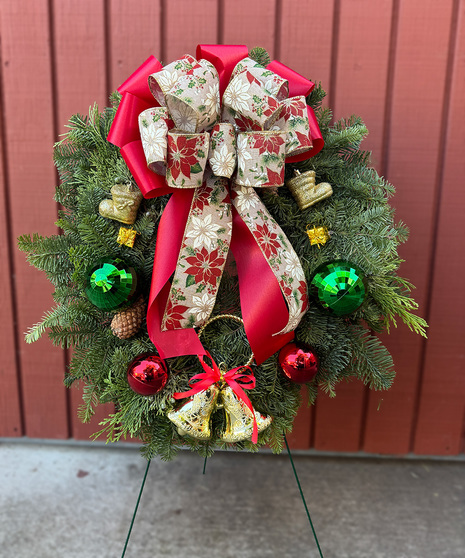 Fresh Christmas wreath with holiday ornaments and a large bow displayed on a 2-foot cemetery stand