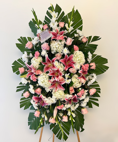 Blushing Tribute Spray with pink lilies, roses, carnations, white hydrangea, pom poms, gladioli, and commodore palm border