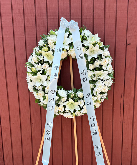 All-white Funeral Wreath with lilies, roses, carnations, and chrysanthemums on stand with Korean condolence banners