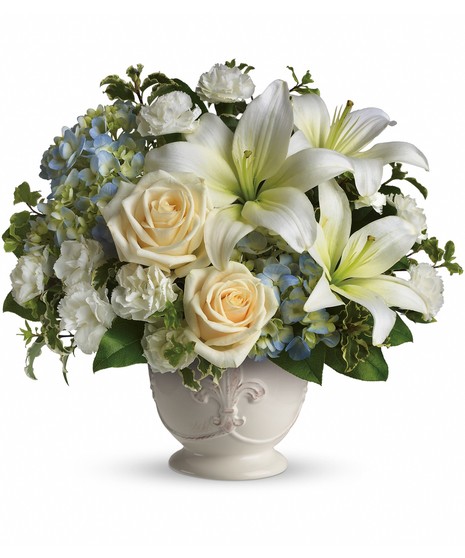 Beautiful Dreams Bouquet with white lilies, ivory roses, blue hydrangea, and carnations in a French Country Pot with Fleur de Lis design.