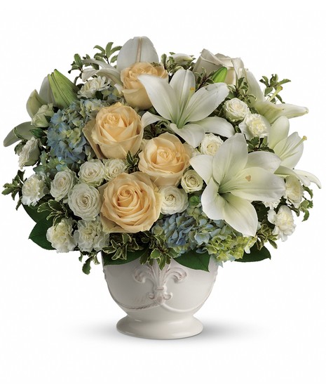 Beautiful Dreams Bouquet with white lilies, ivory roses, blue hydrangea, and carnations in a French Country Pot with Fleur de Lis design.